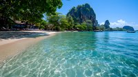 Tropical beach with crystal clear turquoise water and dramatic limestone cliffs under blue sky for travel and vacation concepts.