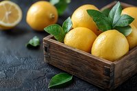Fresh ripe yellow lemons with green leaves in rustic wooden box on dark concrete background, selective focus. Food photography for healthy eating.