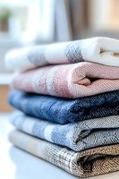 Stack of folded cotton towels in pastel and navy blue colors with plaid pattern, creating cozy bathroom or kitchen textile arrangement.
