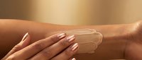Woman applying sunscreen lotion on tanned skin with manicured nails for summer skincare and UV protection routine.