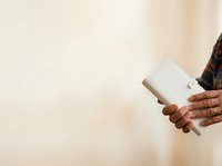 Close-up of hands holding white wallet against neutral beige background, suitable for finance, banking, money management, and lifestyle content.