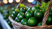 Fresh green limes with water drops in rustic wicker basket against blurred bokeh lights background, macro view of citrus fruits for cocktails and cooking.