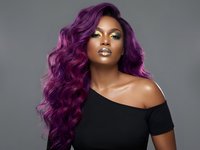 Young African American woman with long curly purple hair wearing black off-shoulder top against gray background for beauty and fashion concepts.