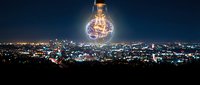 Giant glowing lightbulb with dollar sign filament floating above illuminated city skyline at night representing business innovation and financial success.