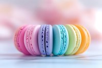Colorful French macarons in pastel rainbow colors of pink, purple, turquoise, mint and yellow arranged in row on light background with soft bokeh effect.