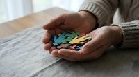 Senior hands holding colorful paper puzzle pieces representing mental health awareness, dementia care, autism support, and therapeutic solutions.