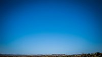 Clear blue sky gradient background with desert landscape horizon for nature and weather designs.