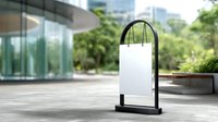 White blank shopping bag mockup on black metal stand near modern glass building entrance with green urban environment and copy space for branding.