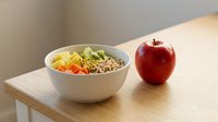 Healthy breakfast bowl with mixed vegetables, grains and fresh red apple on wooden table for nutrition and wellness content.