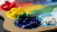 Artist palette with vibrant acrylic paints in rainbow colors on wooden surface for creative painting and art projects.