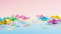 Colorful party confetti and ribbons scattered on pastel background for celebration, birthday, holiday decoration and festive event design.