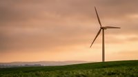 Wind turbine standing in green field at sunset, generating renewable energy for sustainable power production and environmental conservation.