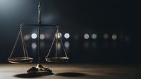 Golden brass scales of justice on wooden desk with blurred city lights background for legal and law firm concepts.