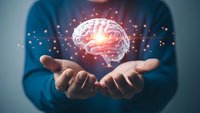 Glowing brain floating above open hands with sparkling light effects representing artificial intelligence, neuroscience and mental health concepts.