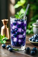 Purple blueberry cocktail with fresh berries and mint garnish in glass with ice cubes on wooden table for summer refreshment and bar menu design.