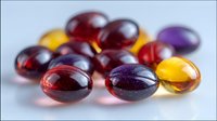 Colorful soft gel capsules in red, purple and yellow scattered on white surface with selective focus creating depth and pharmaceutical appeal.