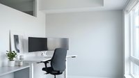 Modern minimalist home office with white desk, ergonomic chair and computer monitor in bright contemporary workspace for remote work and productivity.