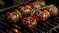 Juicy grilled beef meatballs with vegetables and herbs on barbecue grill with flames and smoke, cooking for summer outdoor party.