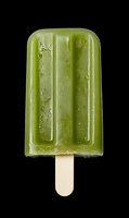 Green matcha or spinach popsicle on wooden stick isolated on black background for summer dessert and healthy frozen treat concepts.