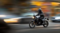 Motorcyclist in black gear riding through city street at night with motion blur effect capturing speed and urban energy for transportation concepts.