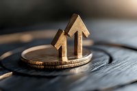 Wooden house shapes placed on stack of coins against dark background, symbolizing real estate investment and property market growth in finance sector.