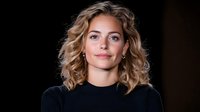 Woman with shoulder-length curly blonde hair wearing black shirt against dark background, suitable for professional portraits, business profiles, and corporate headshots.