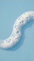 White foam bubbles forming curved shape on soft blue background for cleaning and hygiene concepts.