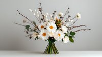 Fresh bouquet of white daisies, dried branches and greenery arranged in rustic style on neutral gray background. Natural floral composition for home decor.