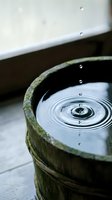 Water droplet creating ripples in wooden barrel with moss-covered rim, zen garden meditation concept for spa wellness and mindfulness practices.