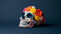 Decorative sugar skull with bright marigold and gerbera flower crown against dark background, celebrating Day of Dead Mexican tradition and folk art culture.