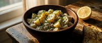 Creamy potato salad with fresh herbs and lemon garnish served in rustic bowl on wooden surface for culinary content.