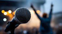 Close-up of microphone with blurred silhouette of performer with raised arms and bokeh lights in background, capturing concert atmosphere.