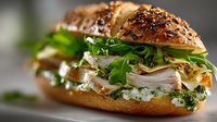 Gourmet sandwich with sliced turkey, fresh arugula and herbs on seeded artisan bun for restaurant menu, food blog or culinary advertising.