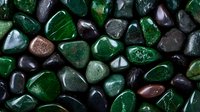 Polished dark green and black stones with wet glossy surface create zen-like pattern. Natural mineral texture background for spa and wellness design.