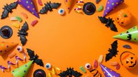 Halloween party decorations and treats arranged in circular frame on bright orange background with copy space for festive seasonal design projects.