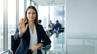 Professional businesswoman making stop gesture with hand in modern office environment, corporate communication and workplace boundaries concept.