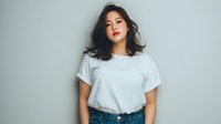 Young Asian woman with shoulder-length dark hair wearing plain white t-shirt and jeans against light blue background, looking confidently at camera.