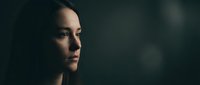 Thoughtful young woman in profile with dramatic lighting against dark background creating moody atmospheric portrait for emotional storytelling.