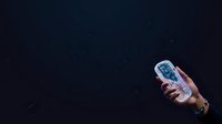 Hand holding a transparent water bottle with blue liquid against dark background, suitable for beverage marketing, product photography, wellness campaigns, and lifestyle advertising.