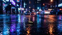Wet urban street at night reflecting neon lights from surrounding buildings and storefronts, creating a moody atmosphere for cityscape and nightlife designs.