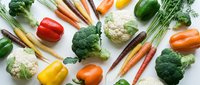 Fresh organic vegetables including broccoli, cauliflower, carrots, bell peppers and herbs arranged on white background for healthy cooking and nutrition.