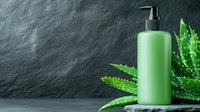 Green cosmetic bottle with pump dispenser against dark textured background with fresh aloe vera leaves, minimalist spa and beauty product photography.