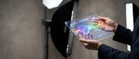 Businessman holding transparent holographic display with colorful digital interface and data visualization in modern office environment for technology and innovation concepts.