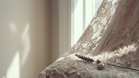 Delicate vintage lace lingerie with pearl jewelry on soft fabric in warm natural sunlight creating romantic feminine atmosphere for intimate fashion photography.