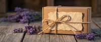 Rustic kraft paper gift boxes tied with natural twine rope surrounded by fresh purple lavender flowers on weathered wooden table for packaging design.