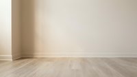 Empty room corner with beige walls and light wooden parquet flooring for interior design and home staging projects.