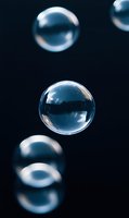 Transparent soap bubbles floating against dark blue background with reflective surfaces and light refraction effects, isolated for design use.