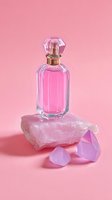 Luxury pink perfume bottle with crystal stopper on rose quartz stone with gemstones against soft pink background for beauty and fragrance branding.