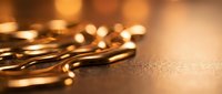Golden coins scattered on warm textured surface with soft bokeh lighting creating wealth and prosperity concept for financial investment themes.