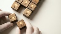 Hands arranging wooden blocks with lightbulb icons representing creative ideas, innovation and problem-solving concepts for business strategy and brainstorming.